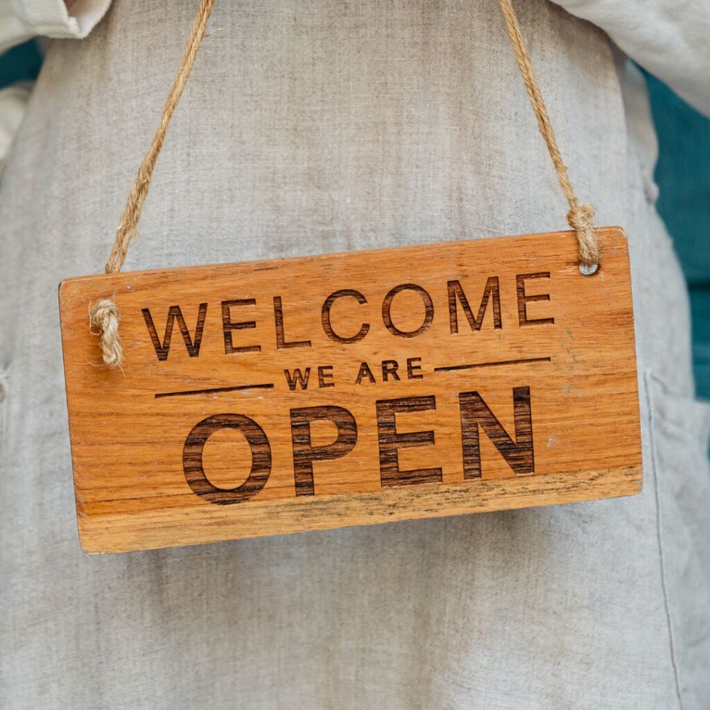 Woman holding open sign. Money Smart for Small Business course