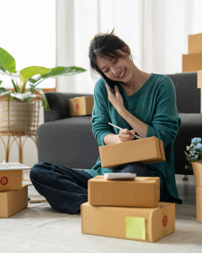 Woman talking on phone sitting near boxes. Small business ideas
